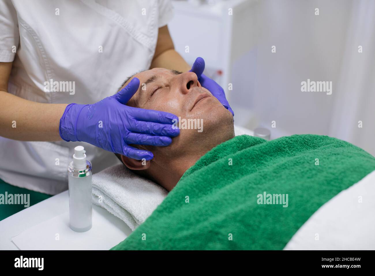Man receiving facial treatment in beauty spa Stock Photo