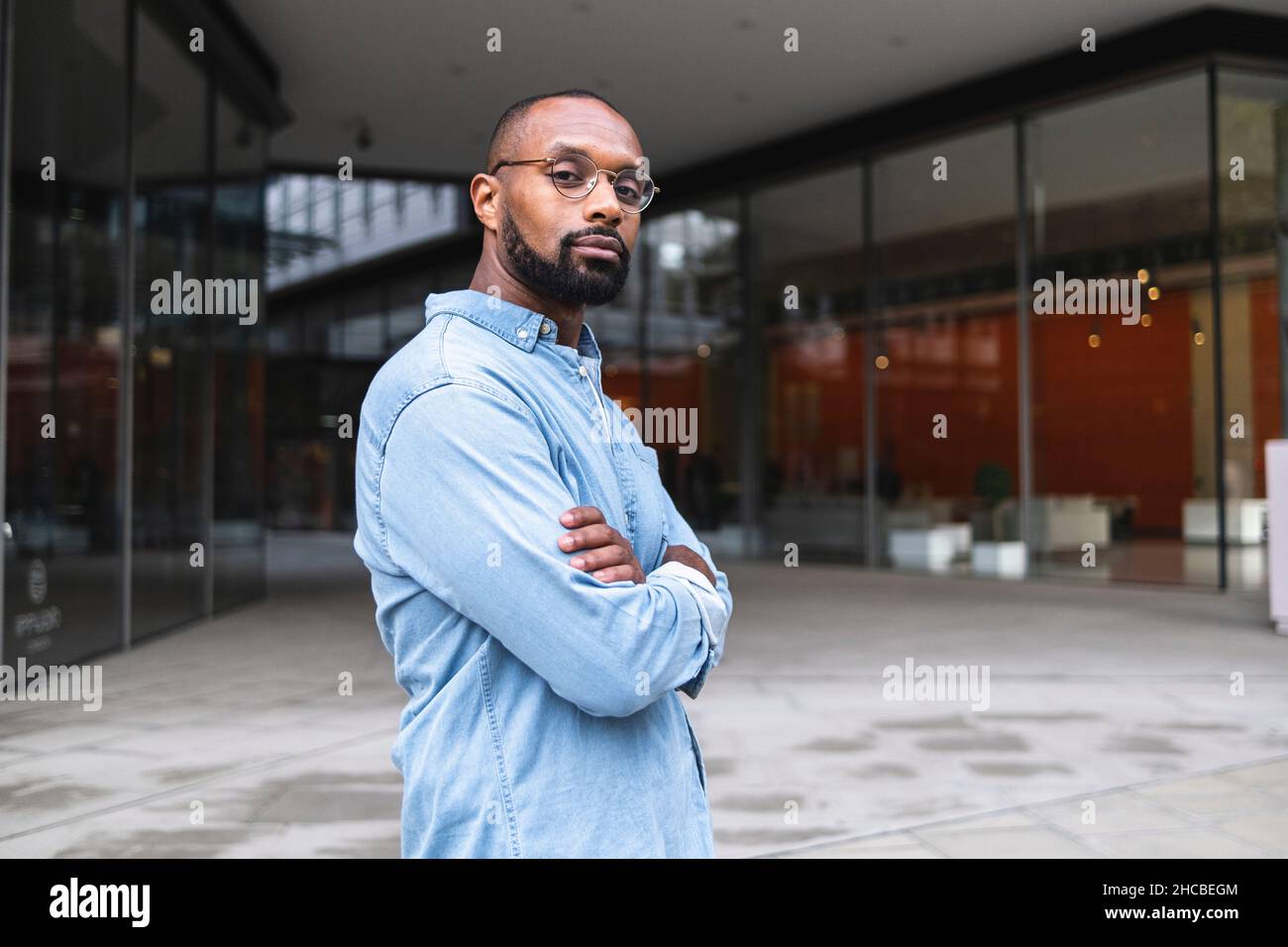 Man with shaved head standing near buildings Stock Photo