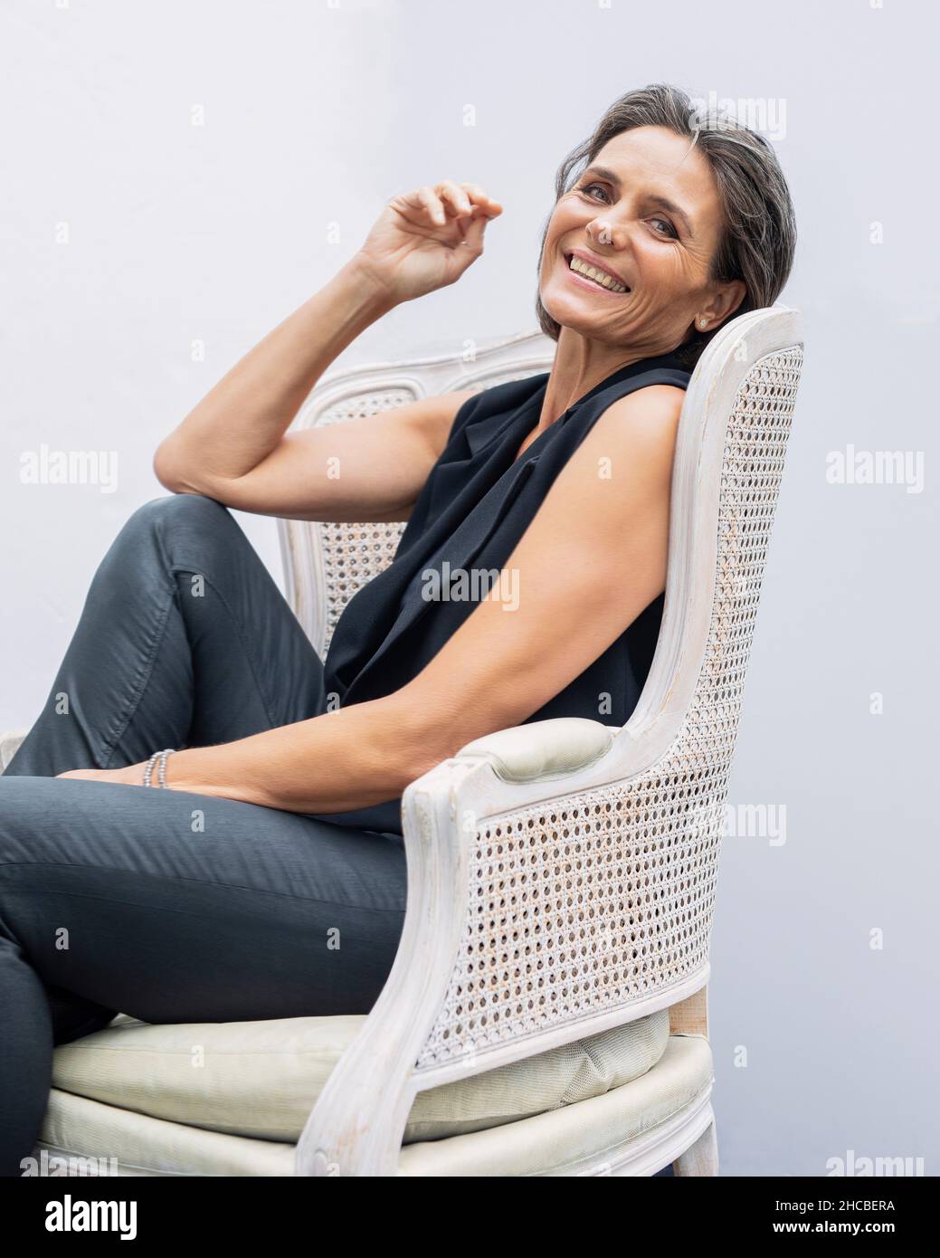 Mature woman sitting on chair against white background Stock Photo - Alamy
