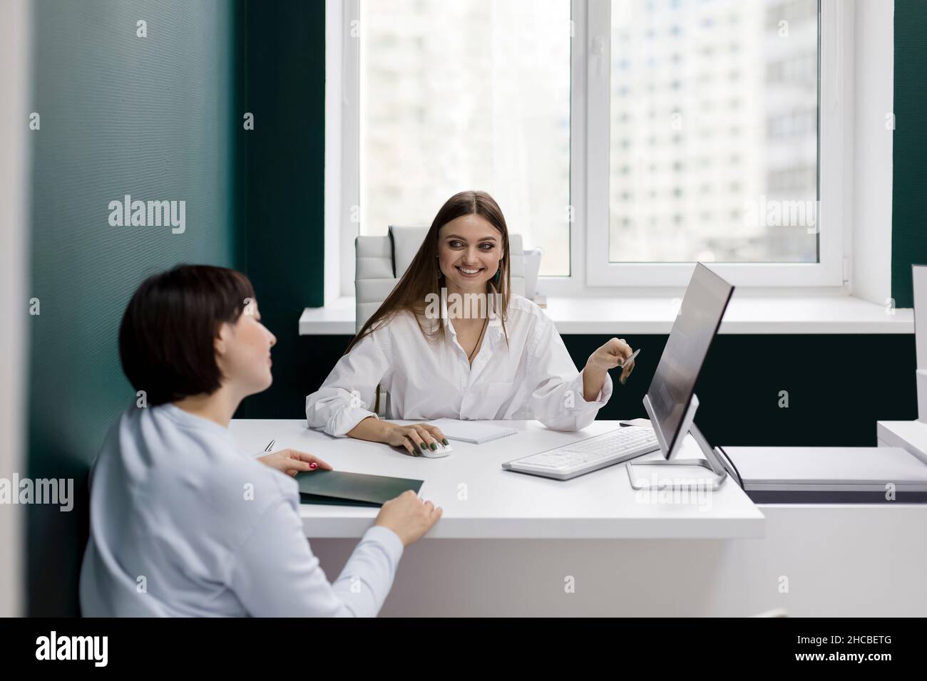 Smiling saleswoman gesturing looking at client in office Stock Photo