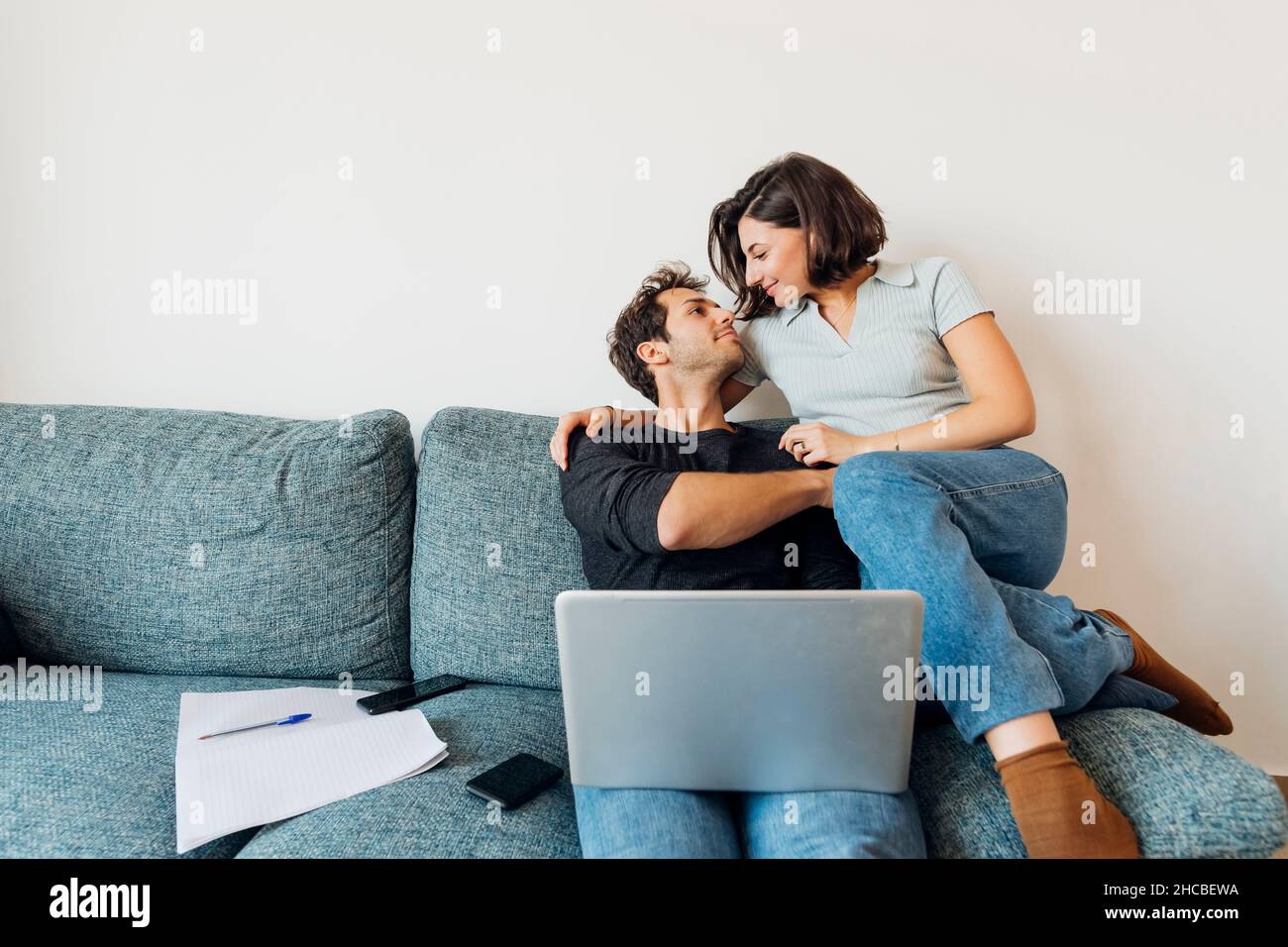 Smiling young couple looking at each other while working at home Stock Photo