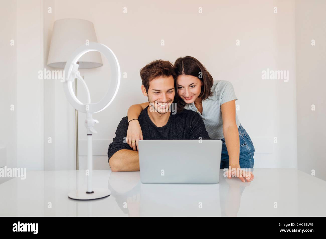 Smiling young couple using laptop together on table at home Stock Photo