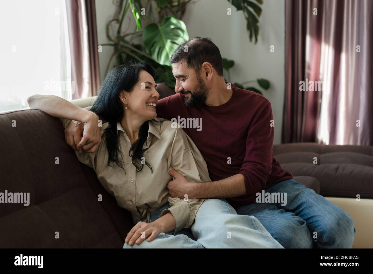 Smiling woman sitting with man on sofa Stock Photo