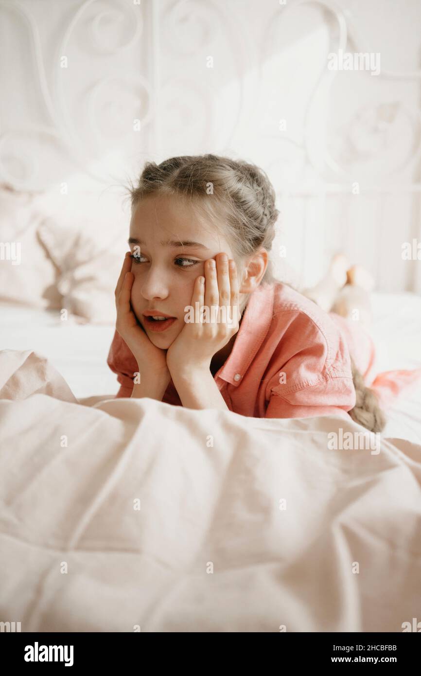 Contemplating girl lying on bed at home Stock Photo Alamy