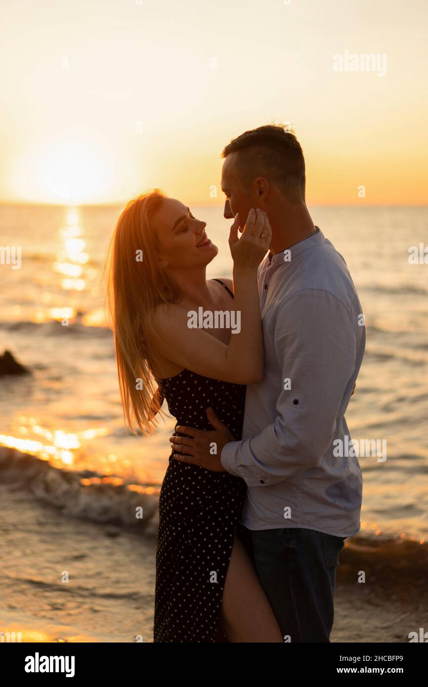 Romantic young couple enjoying sunset at beach Stock Photo - Alamy
