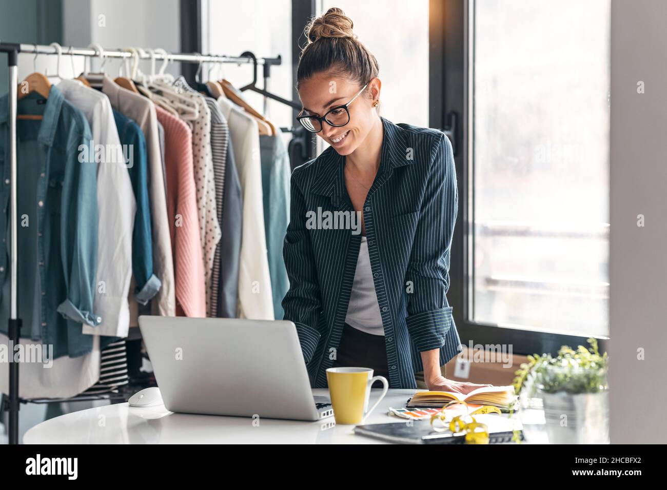 Smiling fashion designer using laptop in office Stock Photo