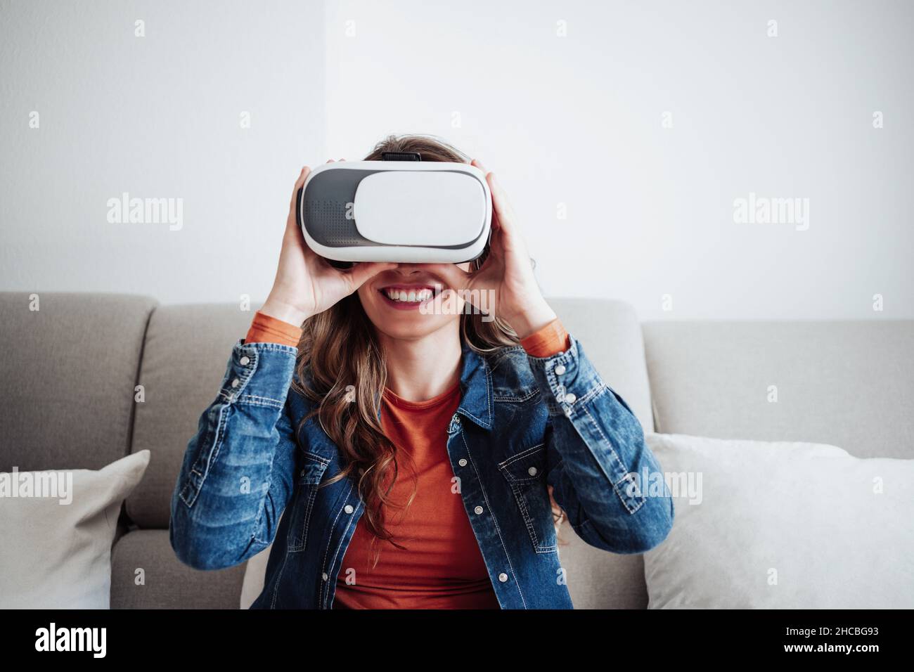 Smiling woman using virtual reality simulator at home Stock Photo