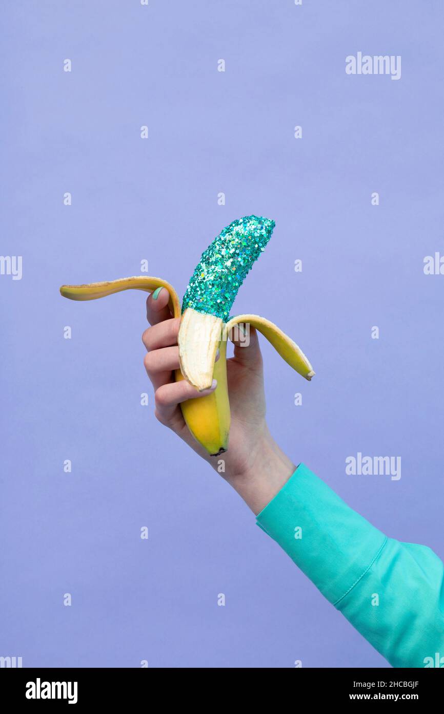 Teenage girl holding banana by lavender background Stock Photo