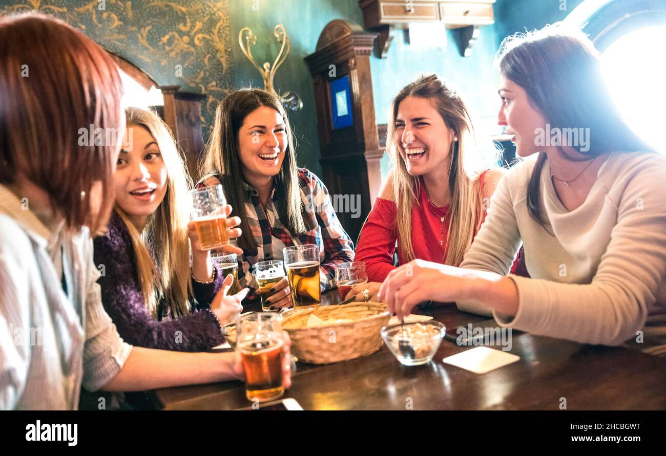 Happy women drinking beer at brewery restaurant - Female friendship concept with young girlfriends enjoying time together and having genuine fun Stock Photo