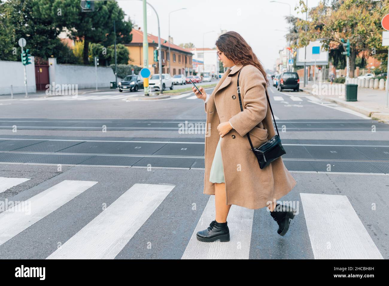 Plus size woman using smart phone while crossing road Stock Photo