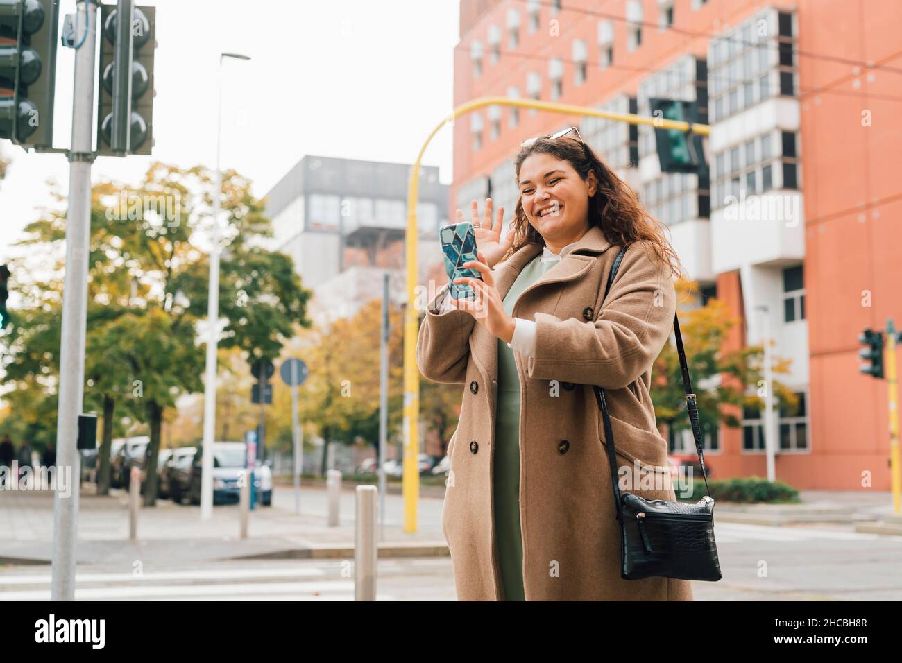 Happy plus size woman waving on video call through smart phone Stock Photo