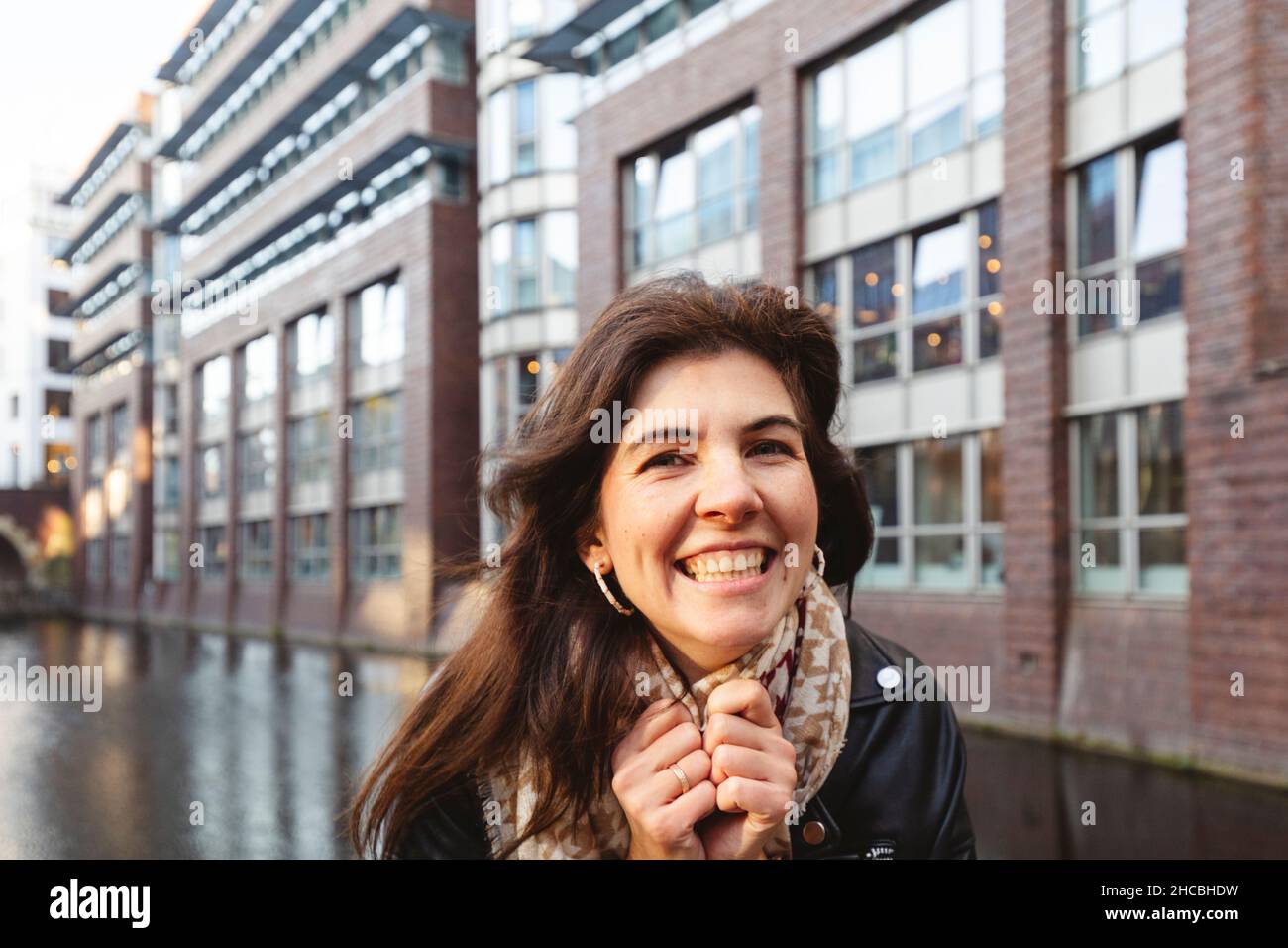 Thoughtful woman wearing scarf and jacket at canal Stock Photo