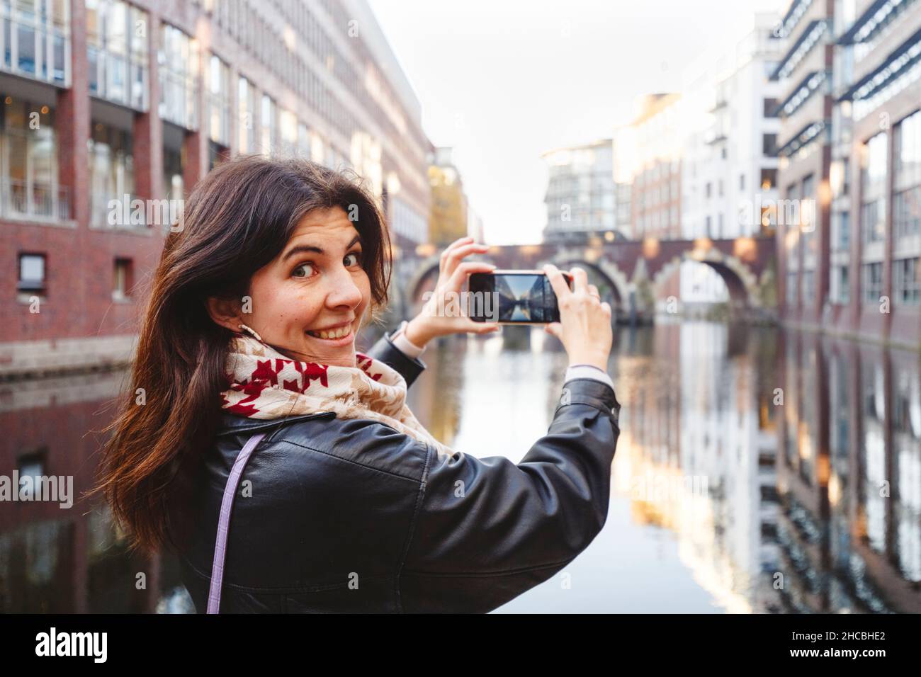 Woman photographing Ellerntorsbrucke bridge through mobile phone at canal Stock Photo