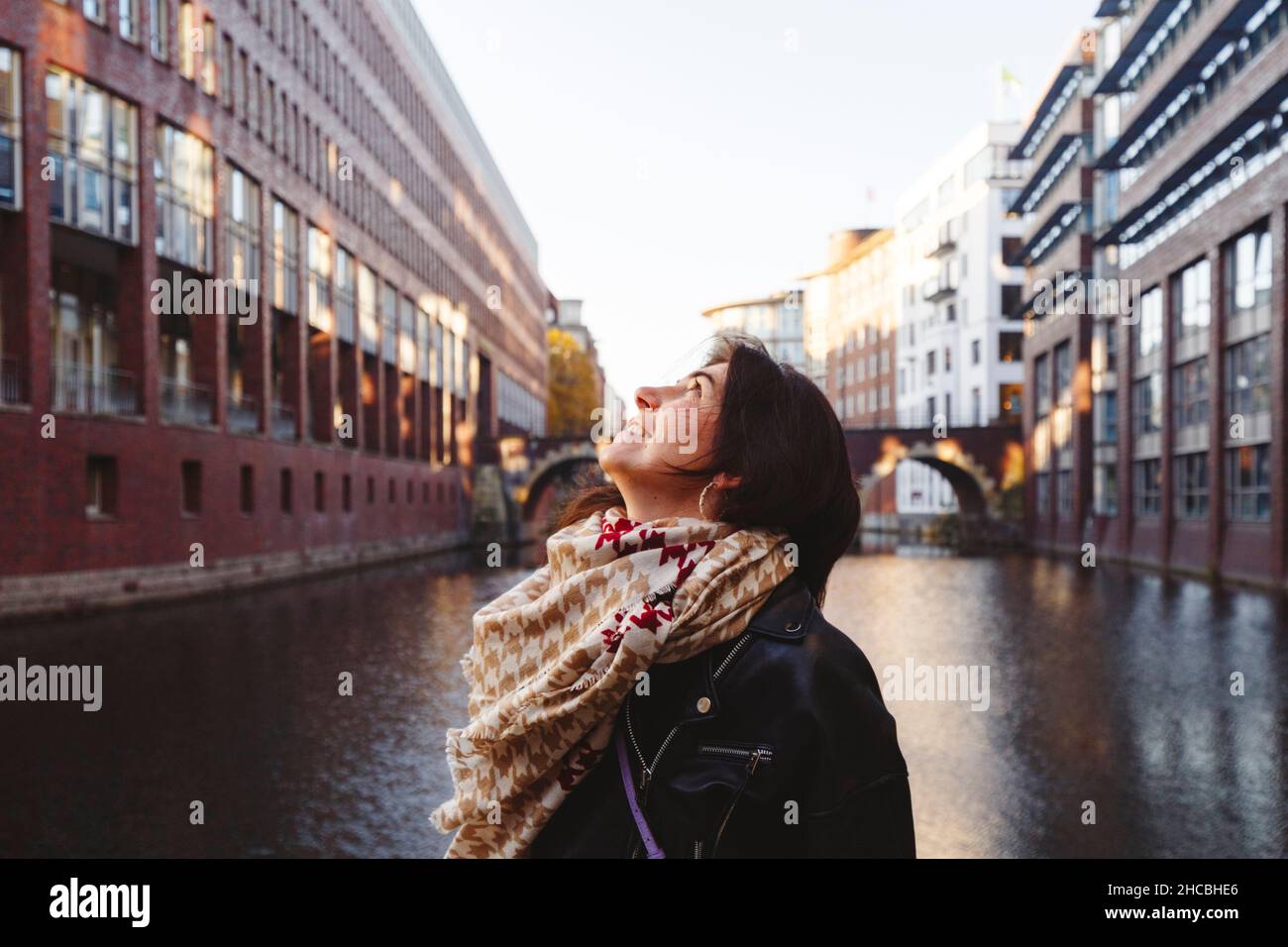Smiling woman photographing Ellerntorsbrucke bridge through mobile phone at canal Stock Photo