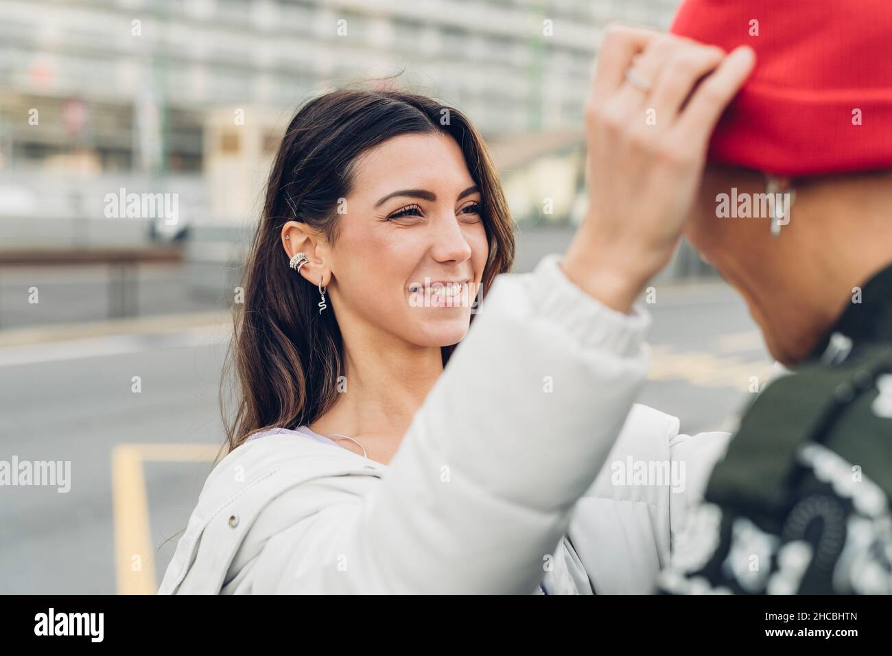 Smiling woman adjusting boyfriend's knit hat Stock Photo