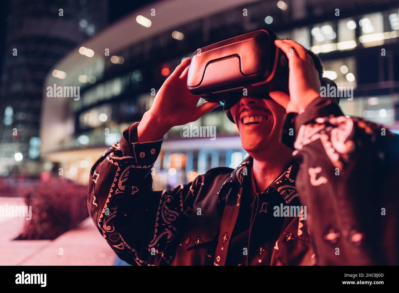 Young man using virtual reality headset at night in city Stock Photo