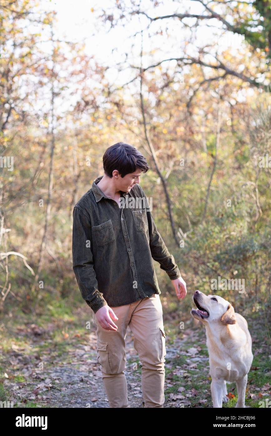 Young man with dog walking in autumn forest on weekend Stock Photo