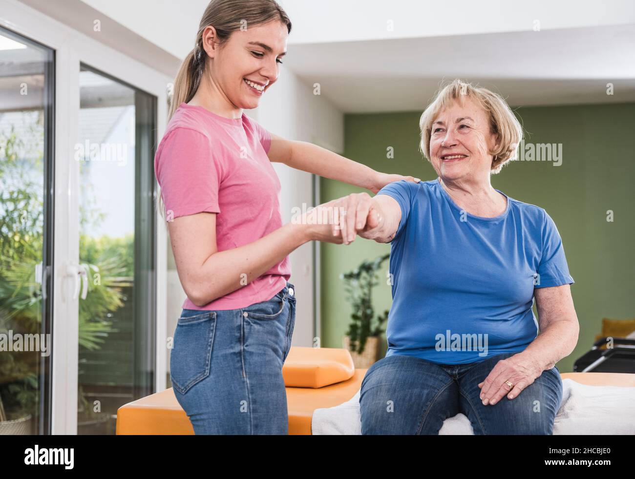 Physical therapist stretching disabled woman's hand at home Stock Photo