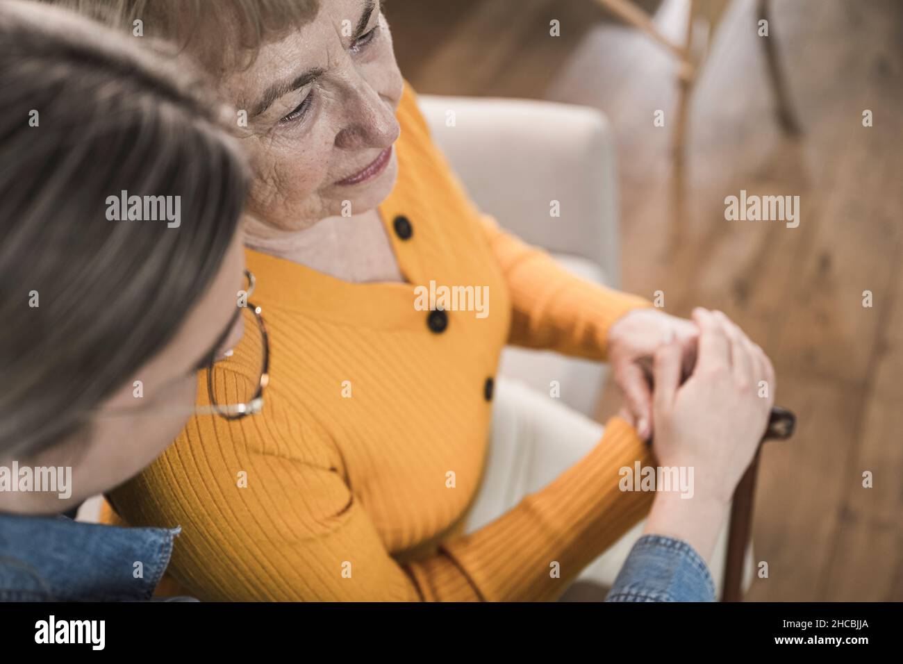 Caregiver consoling senior woman at home Stock Photo