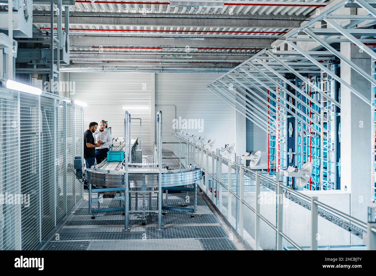 Warehouse manager working with colleague at conveyor belt in industry