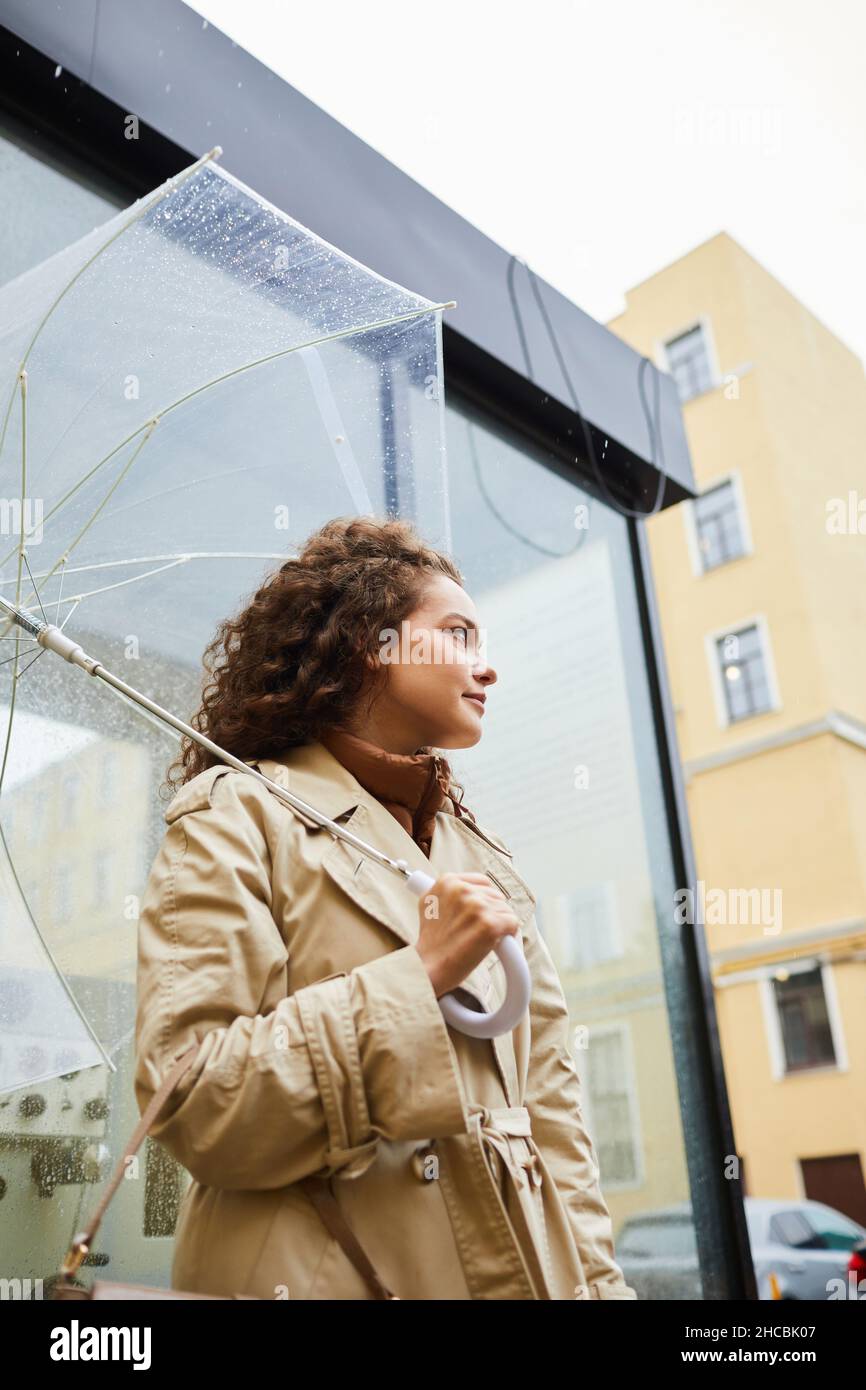 Vertical low angle shot of young woman wearing beige trench coat ...