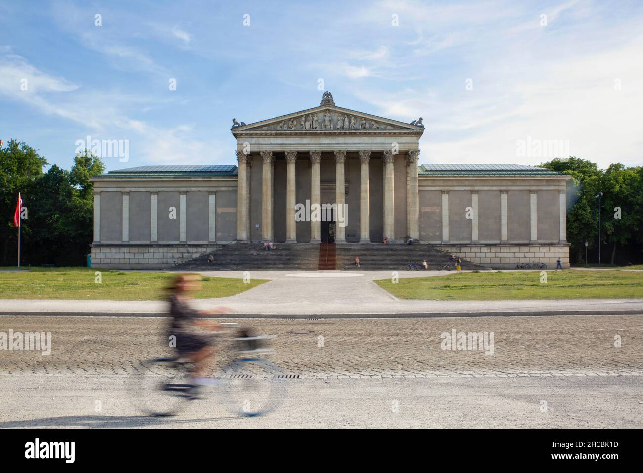 Germany, Bavaria, Munich, Woman riding bicycle past Staatliche Antikensammlung museum Stock Photo