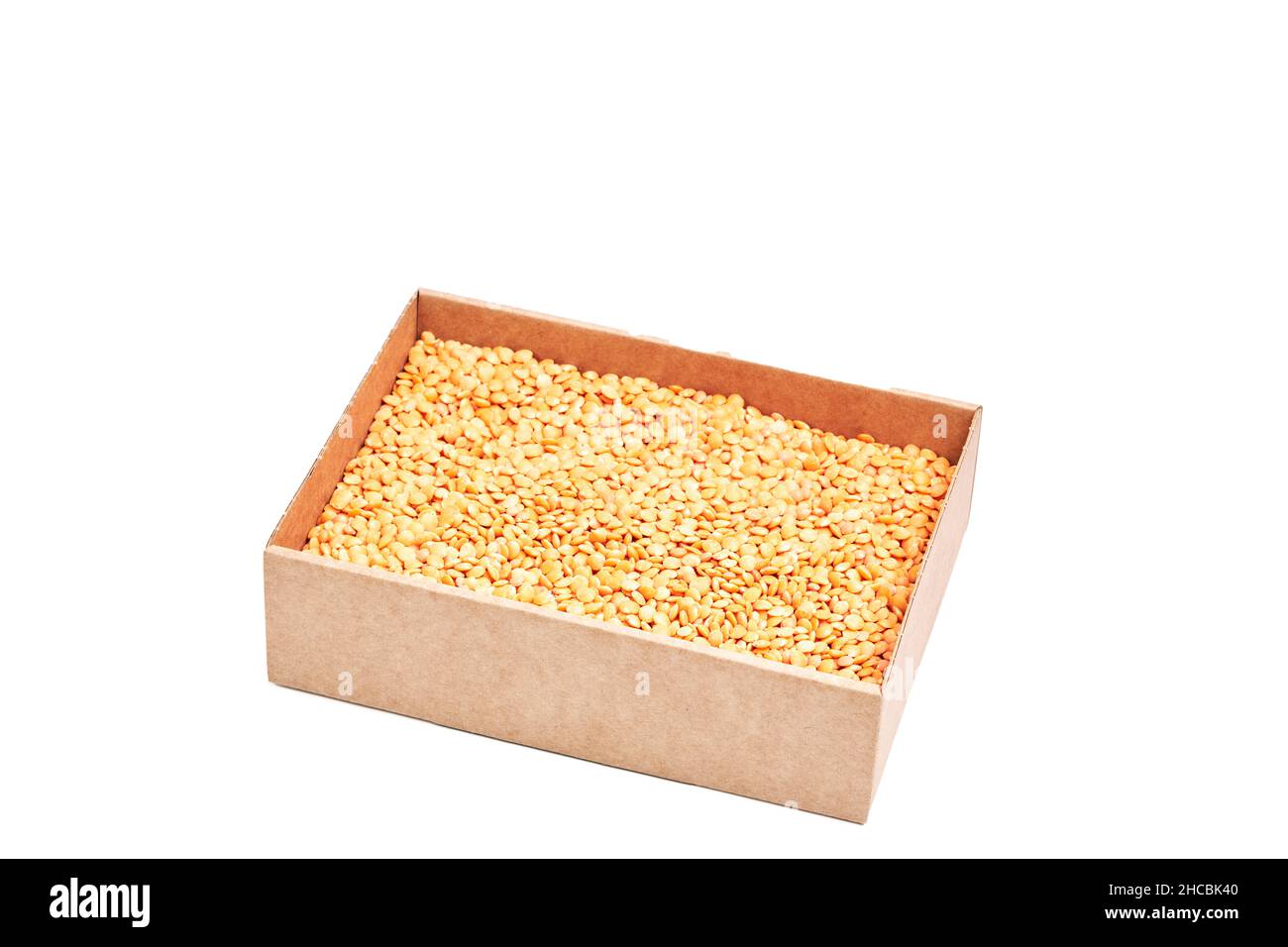 Cardboard box full of raw orange lentils on a white background. Healthy food concept Stock Photo