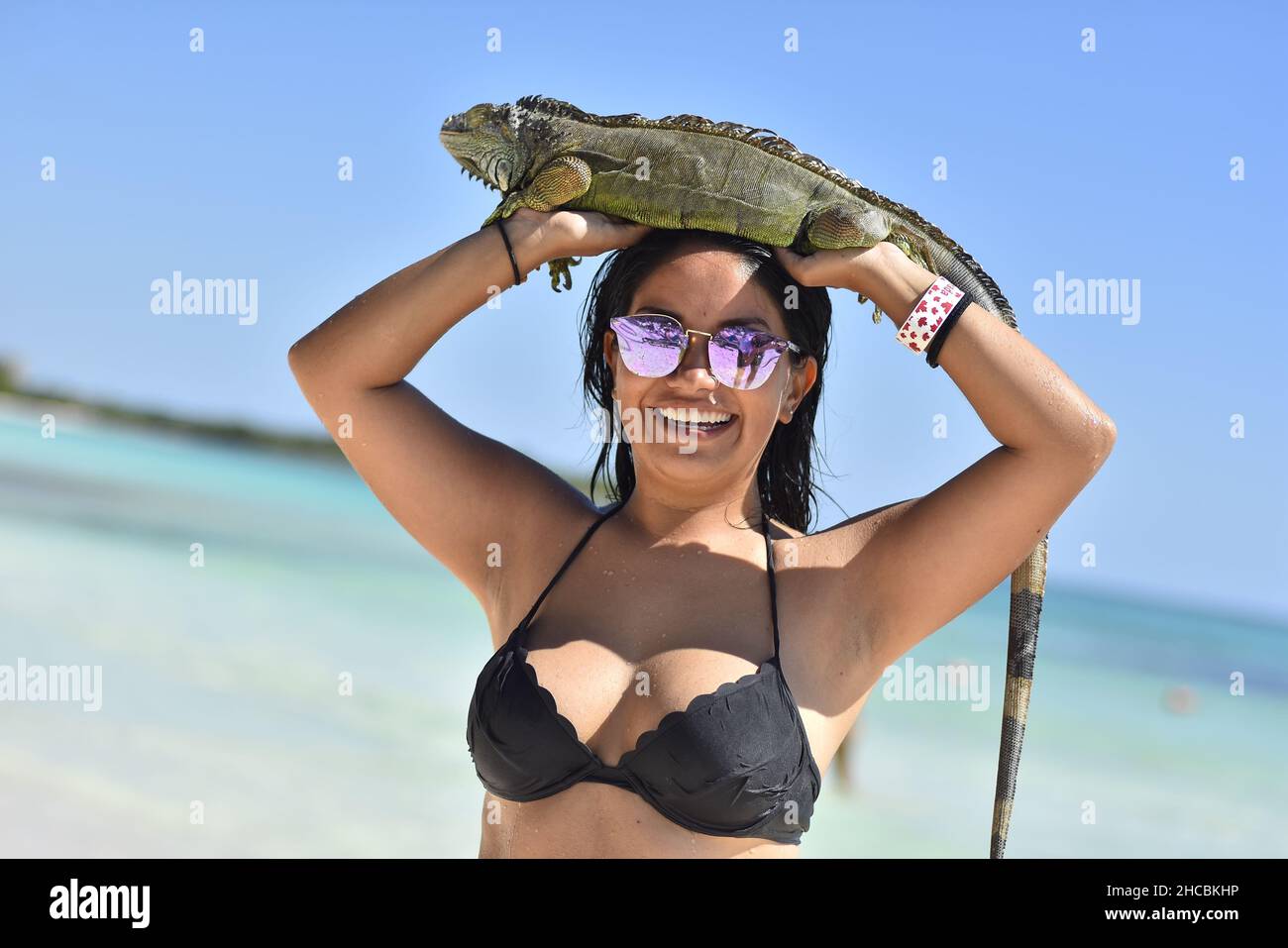 Portrait of Mexican girl with iguana in mexican beach in a sunny day Stock Photo