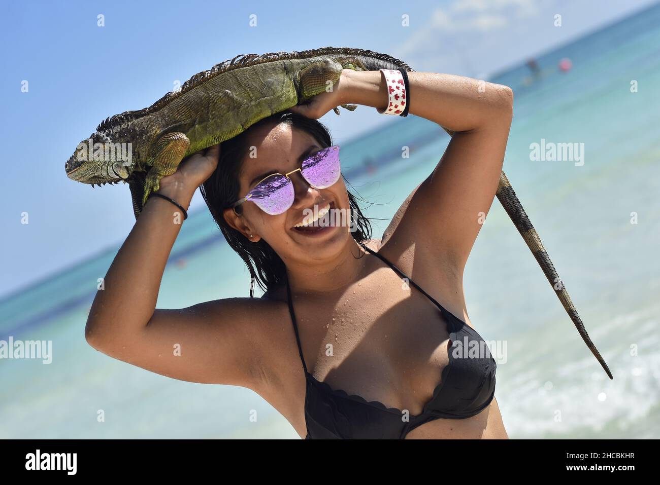 Portrait of Mexican girl with iguana in mexican beach in a sunny day Stock Photo