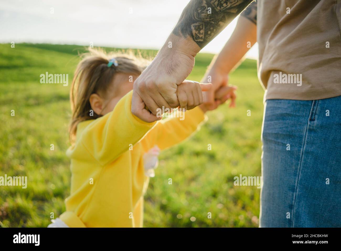 Father and daughter holding hands standing on grass Stock Photo - Alamy