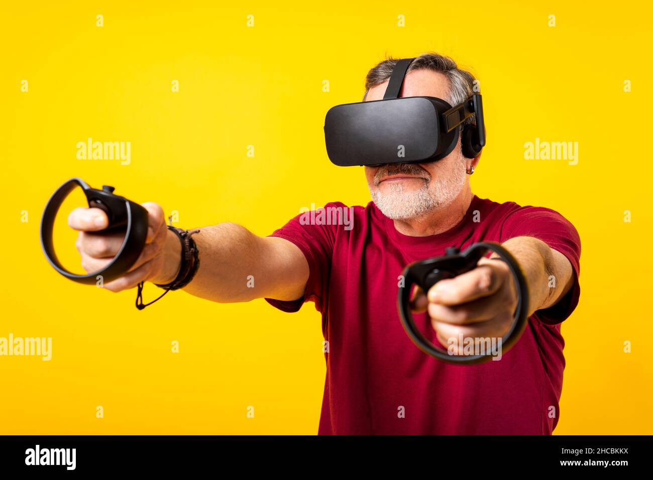 Man wearing virtual headset holding controller against yellow
