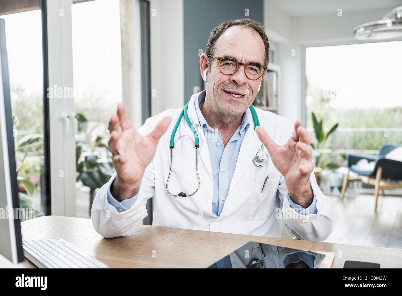 Doctor wearing eyeglasses gesturing at desk in hospital Stock Photo Alamy