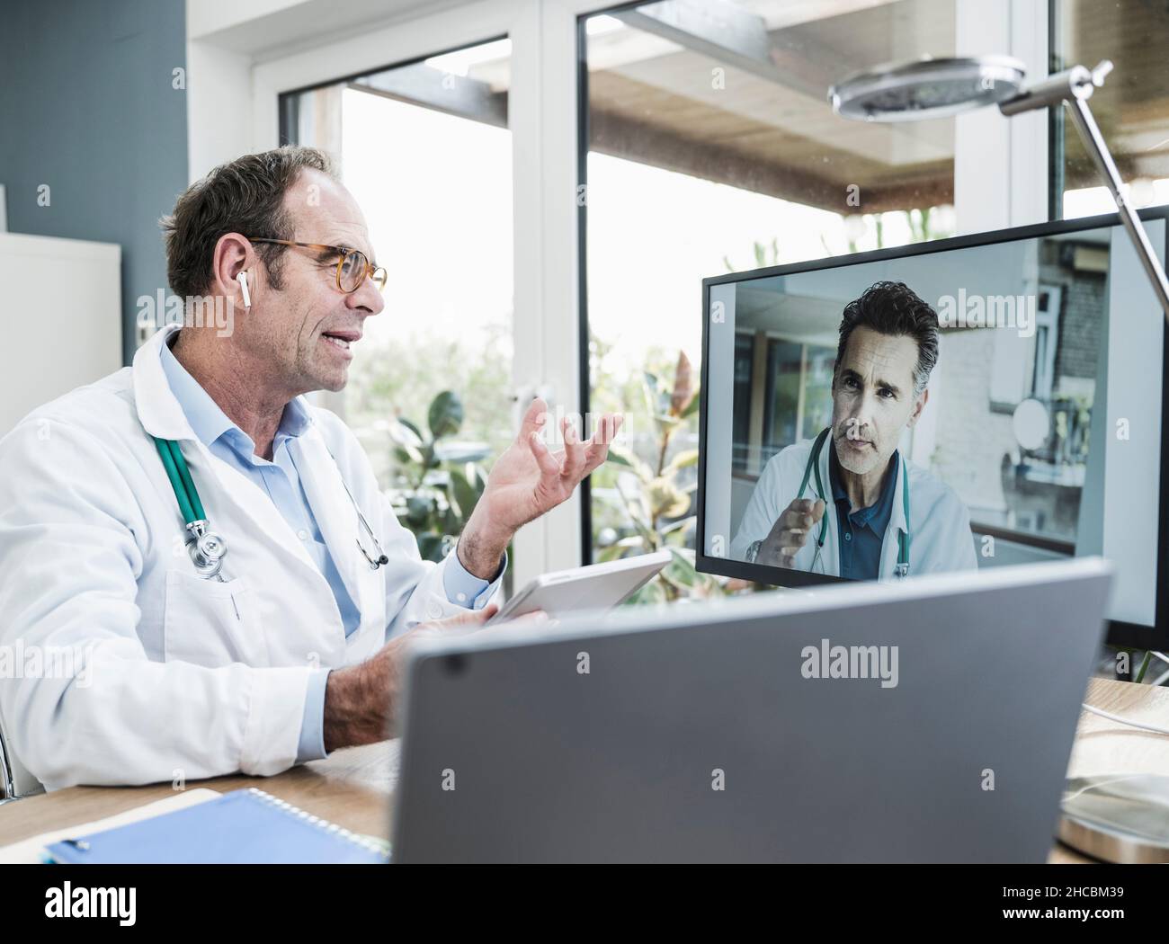 Doctor talking with colleague on video call through computer in clinic ...