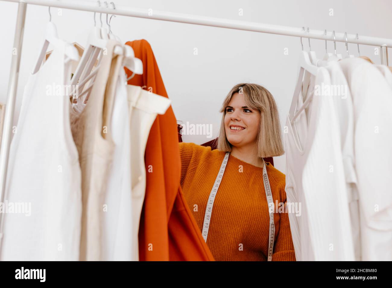 Businesswoman looking at dress hanging on clothes rack at workshop Stock Photo