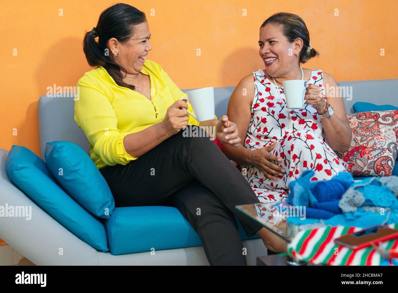 Two happy women sitting together on a sofa with cups of coffee Stock ...