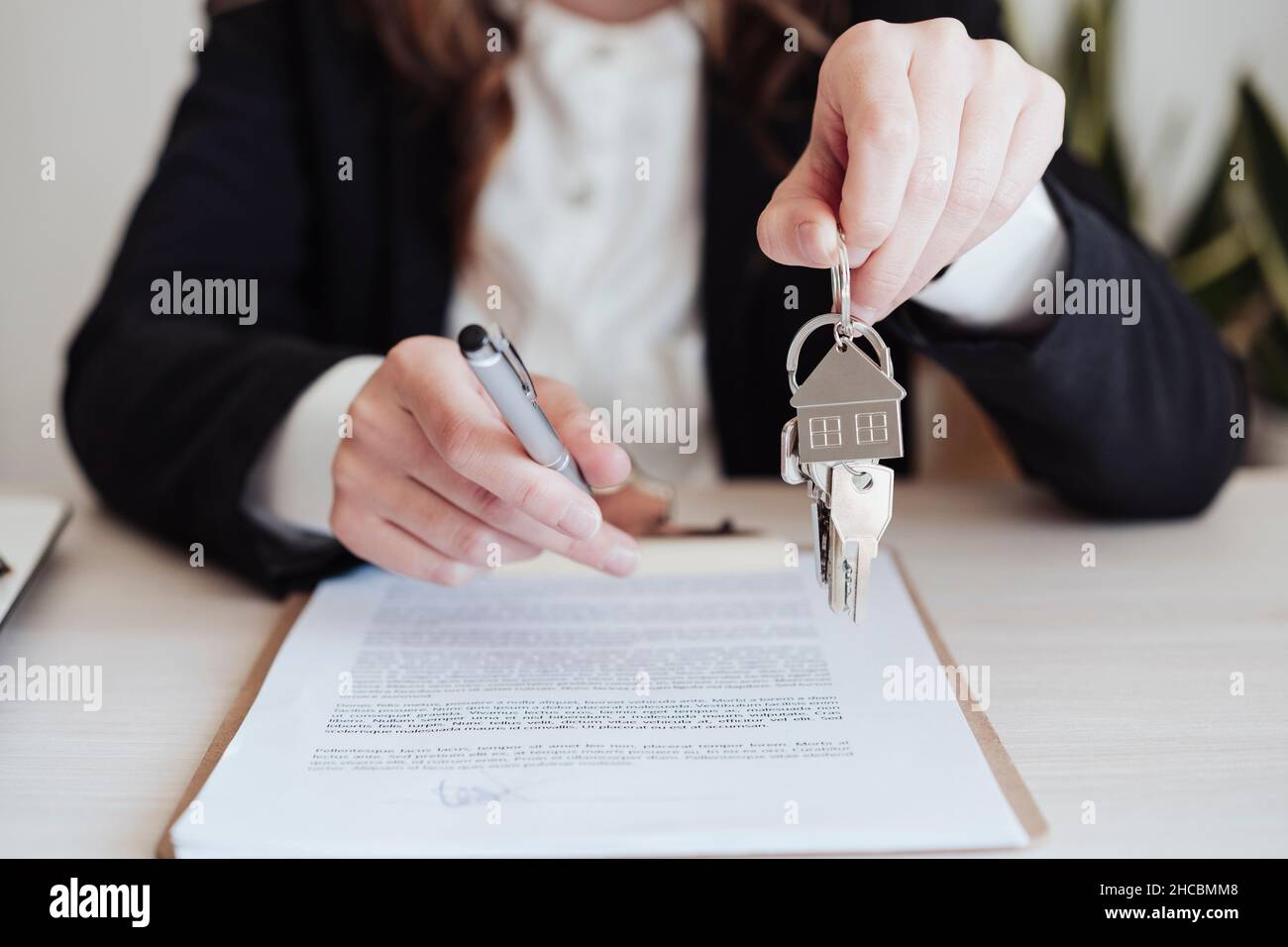 Saleswoman holding house keys and pen at office Stock Photo