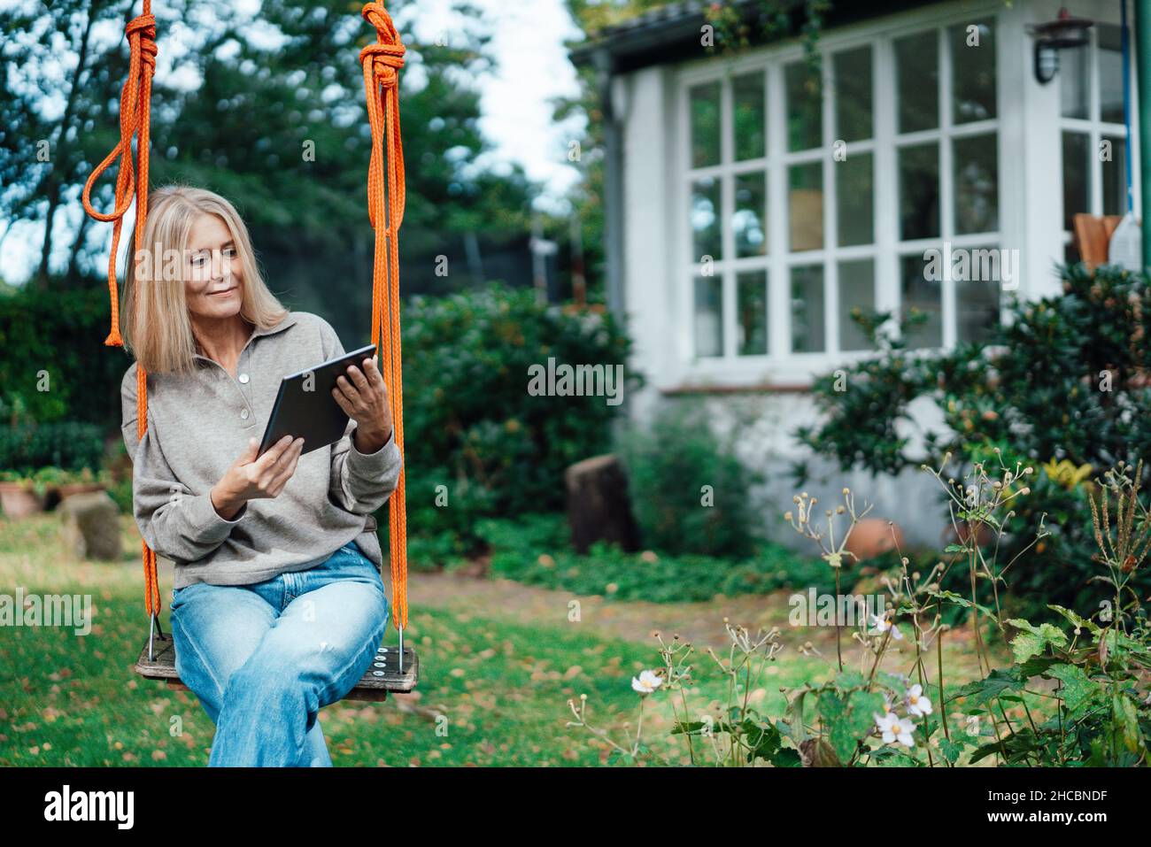 Blond woman using tablet PC at backyard Stock Photo
