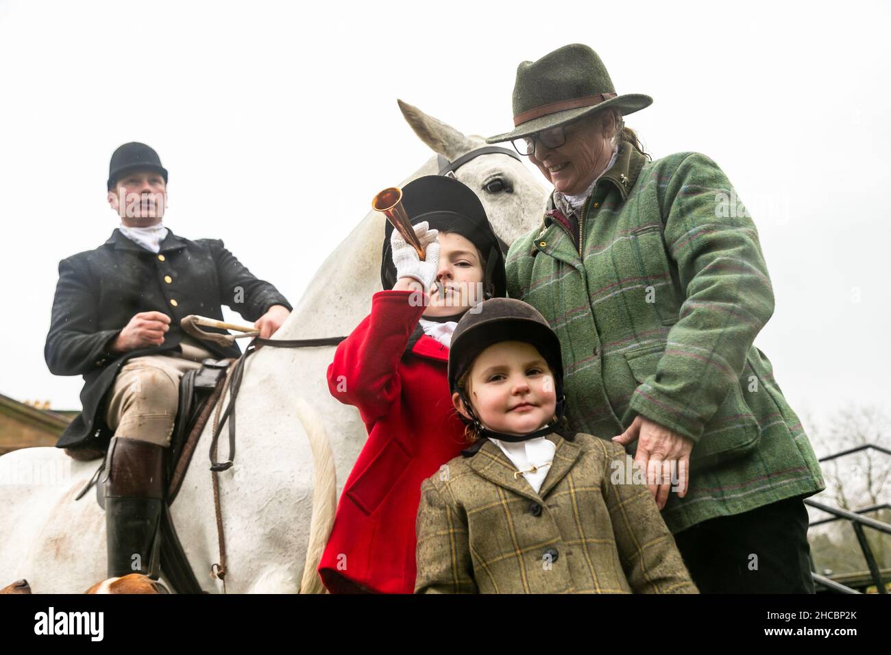 Hagley, Worcestershire, UK. 27th Dec, 2021. 8-year-old Henley Mills stands with his sister Myla-May, 2, and grandmother Jane, among the hounds the first hunt at Hagley Hall since the Coronavirus pandemic. The Albrighton and Woodland Hunt meet annually at Hagley Hall in Worcestershire. Credit: Peter Lopeman/Alamy Live News Stock Photo