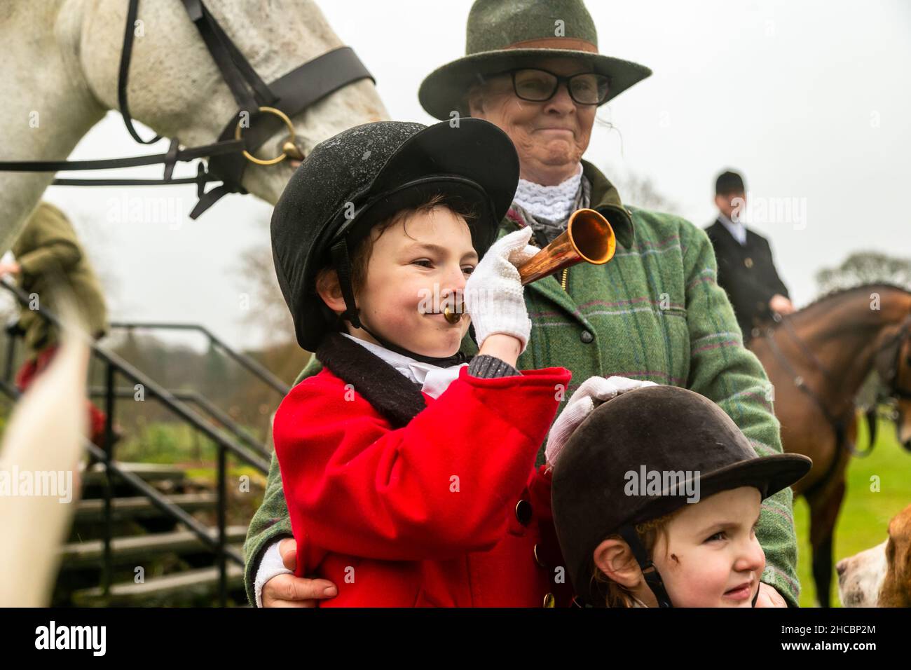 Hagley, Worcestershire, UK. 27th Dec, 2021. 8-year-old Henley Mills stands with his sister Myla-May, 2, and grandmother Jane, among the hounds the first hunt at Hagley Hall since the Coronavirus pandemic. The Albrighton and Woodland Hunt meet annually at Hagley Hall in Worcestershire. Credit: Peter Lopeman/Alamy Live News Stock Photo