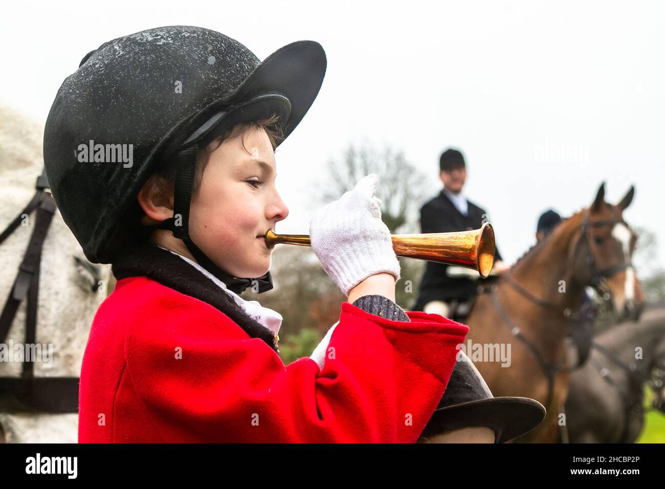 Hagley, Worcestershire, UK. 27th Dec, 2021. 8-year-old Henley Mills blows his horn at the first Albrighton and Woodland Hunt meet at Hagley Hall since the Coronavirus pandemic. The Albrighton and Woodland Hunt meet annually at Hagley Hall in Worcestershire. Credit: Peter Lopeman/Alamy Live News Stock Photo
