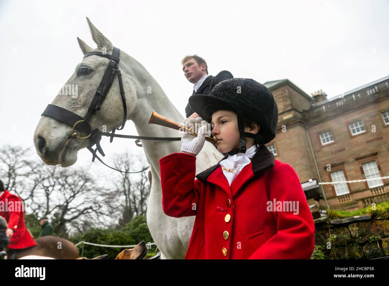 Hagley, Worcestershire, UK. 27th Dec, 2021. 8-year-old Henley Mills blows his horn at the first Albrighton and Woodland Hunt at Hagley Hall since the Coronavirus pandemic. The Albrighton and Woodland Hunt meet annually at Hagley Hall in Worcestershire. Credit: Peter Lopeman/Alamy Live News Stock Photo