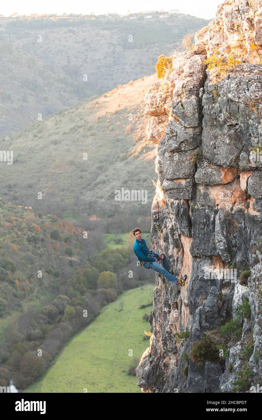 Man with safety harness clambering rock cliff Stock Photo