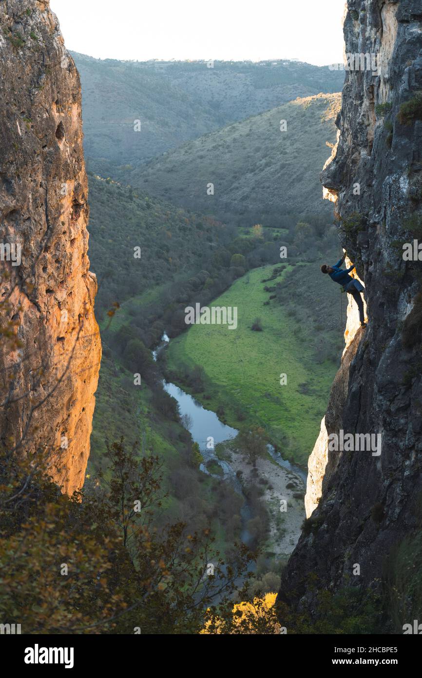 Hiker with climbing rope hanging on rock mountain Stock Photo