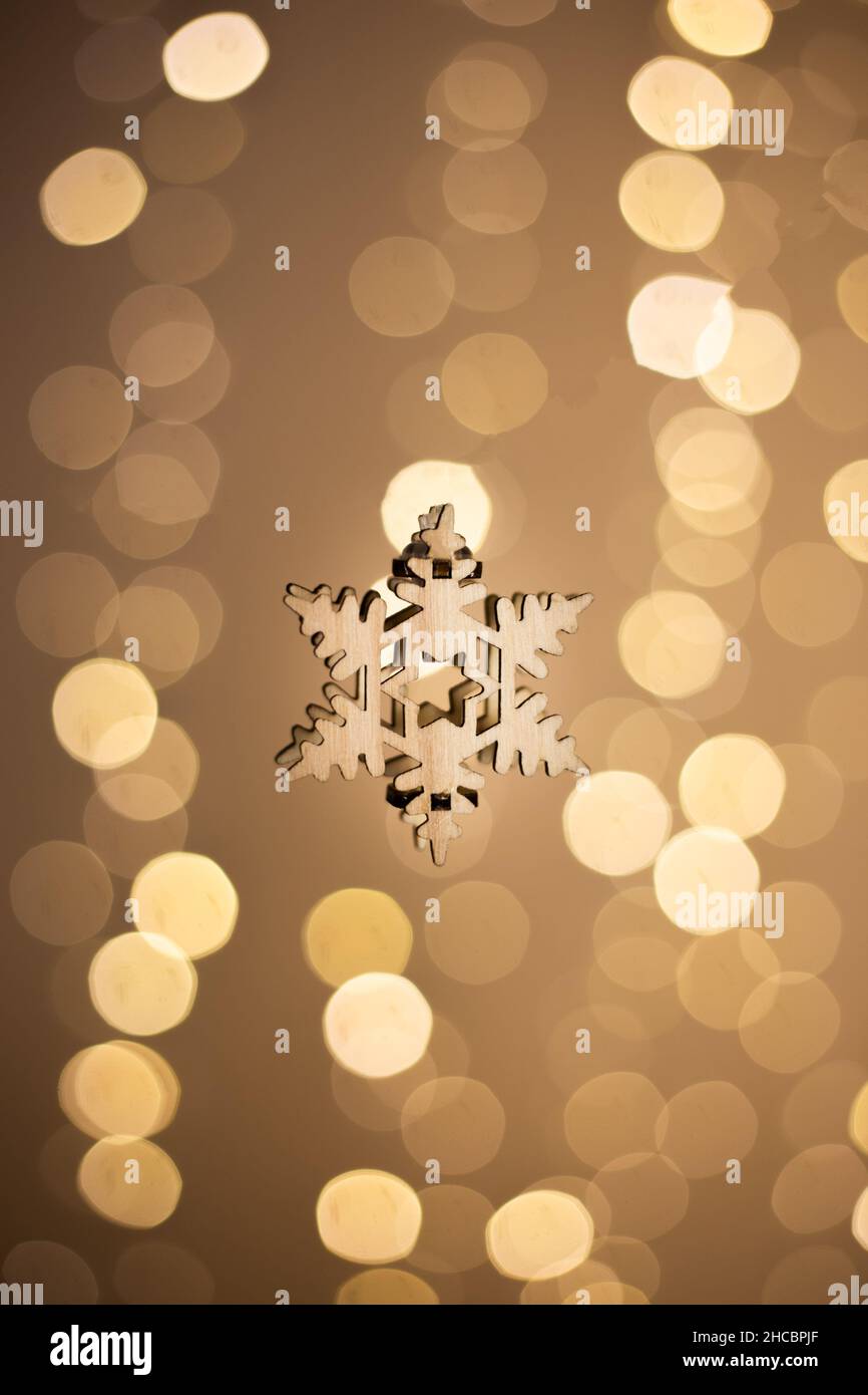 Wooden ornamental snowflake for Christmas against a blurry background with bokeh lights Stock Photo