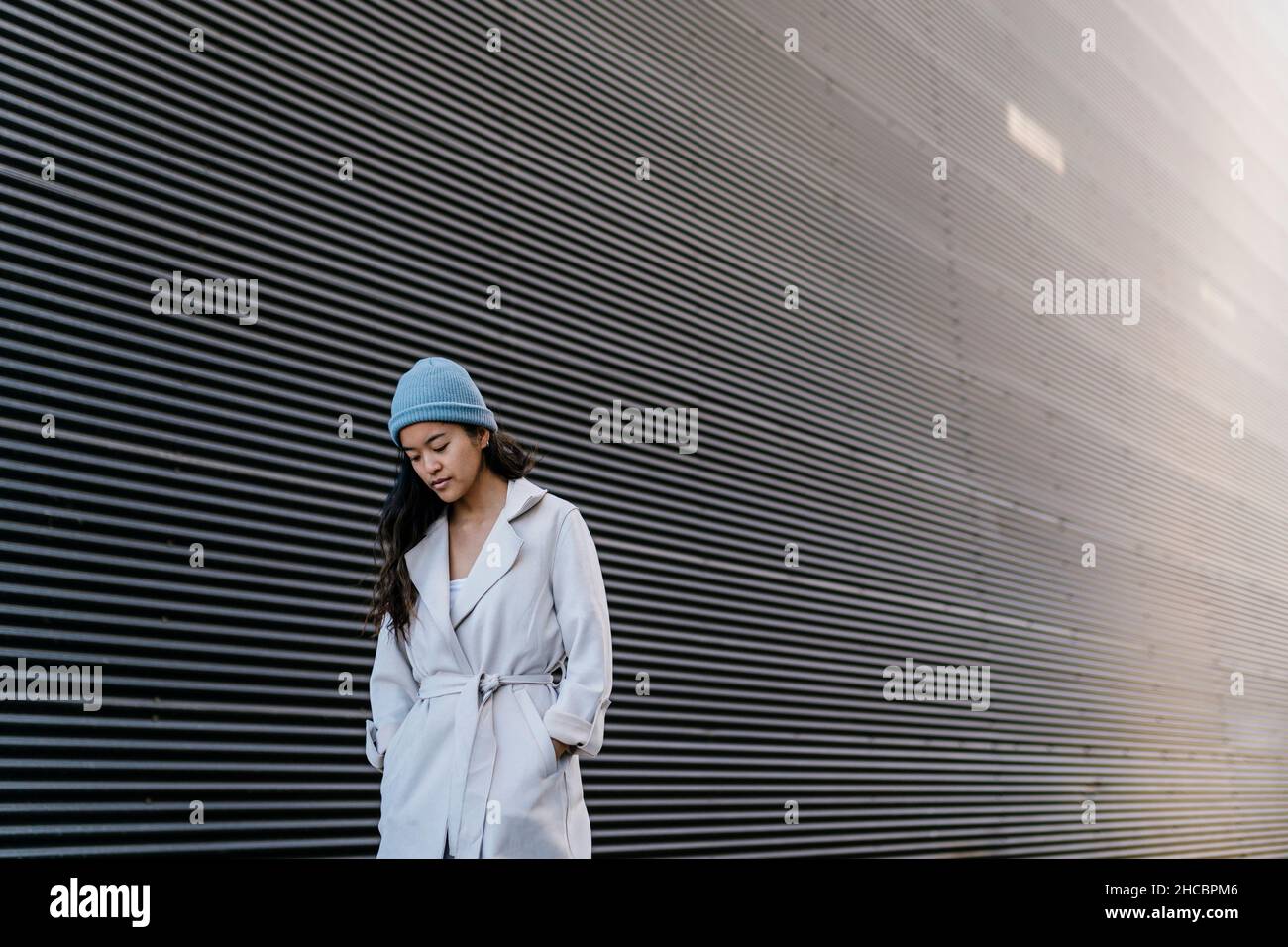 Woman standing with hands in pockets at black wall Stock Photo - Alamy