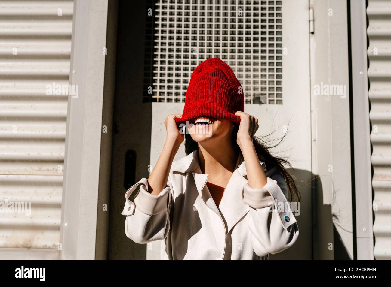 Woman hiding face with knit hat in front of door Stock Photo Alamy