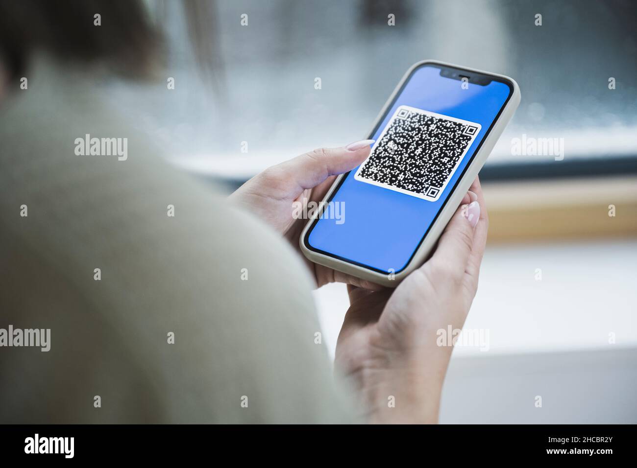 Woman holding mobile phone with QR code on screen Stock Photo