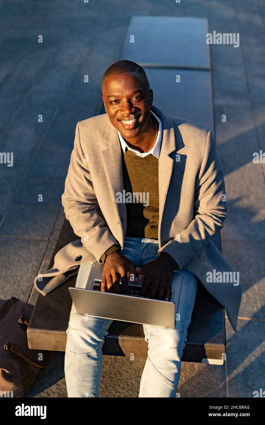 Smiling businessman sitting on bench Stock Photo