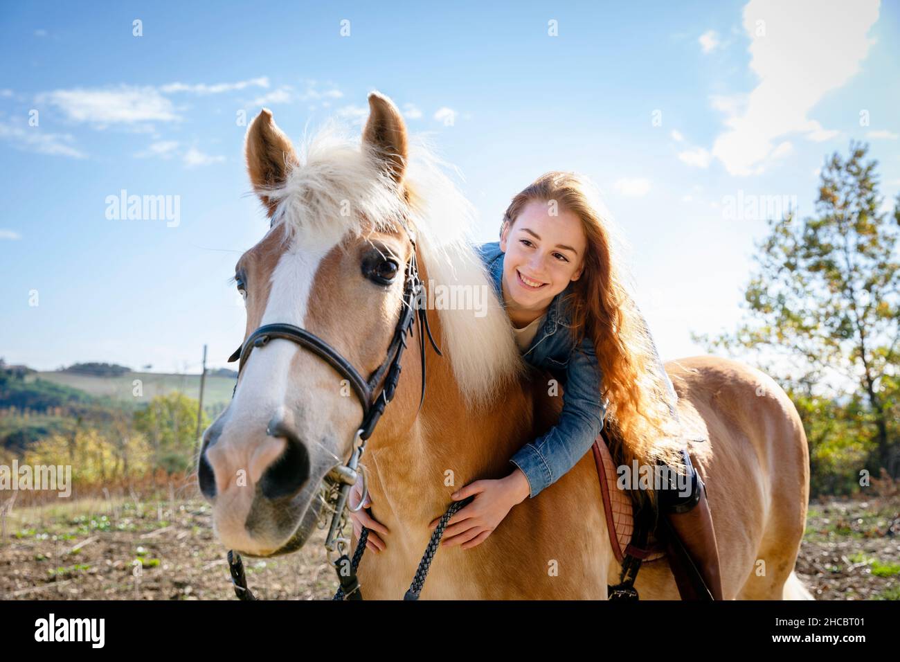 Smiling woman sitting on horse at meadow during weekend Stock Photo