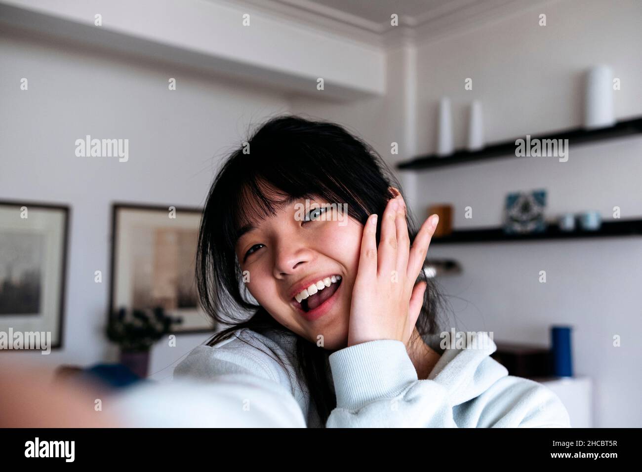 Cheerful young woman taking selfie at home Stock Photo